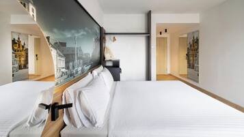 Une chambre d’hôtel avec deux lits, un grand tableau représentant un paysage urbain et une tête de lit en bois.
