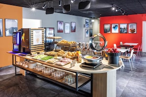 Un bufé de desayuno con diferentes alimentos y una máquina de café.