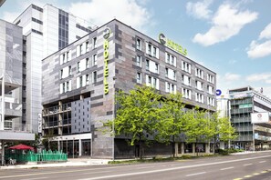 Un moderno edificio de hotel con un llamativo letrero de B&B Hotels, varios pisos y un estacionamiento.