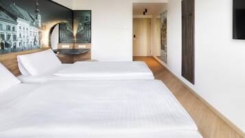 A hotel room with two beds, a large wall mural, and a wooden floor.