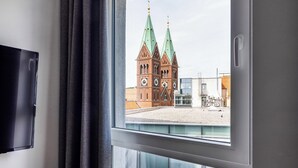 A window with a view of a historic building with two spires and a clock tower. - B&B Hotel Maribor (Maribor)