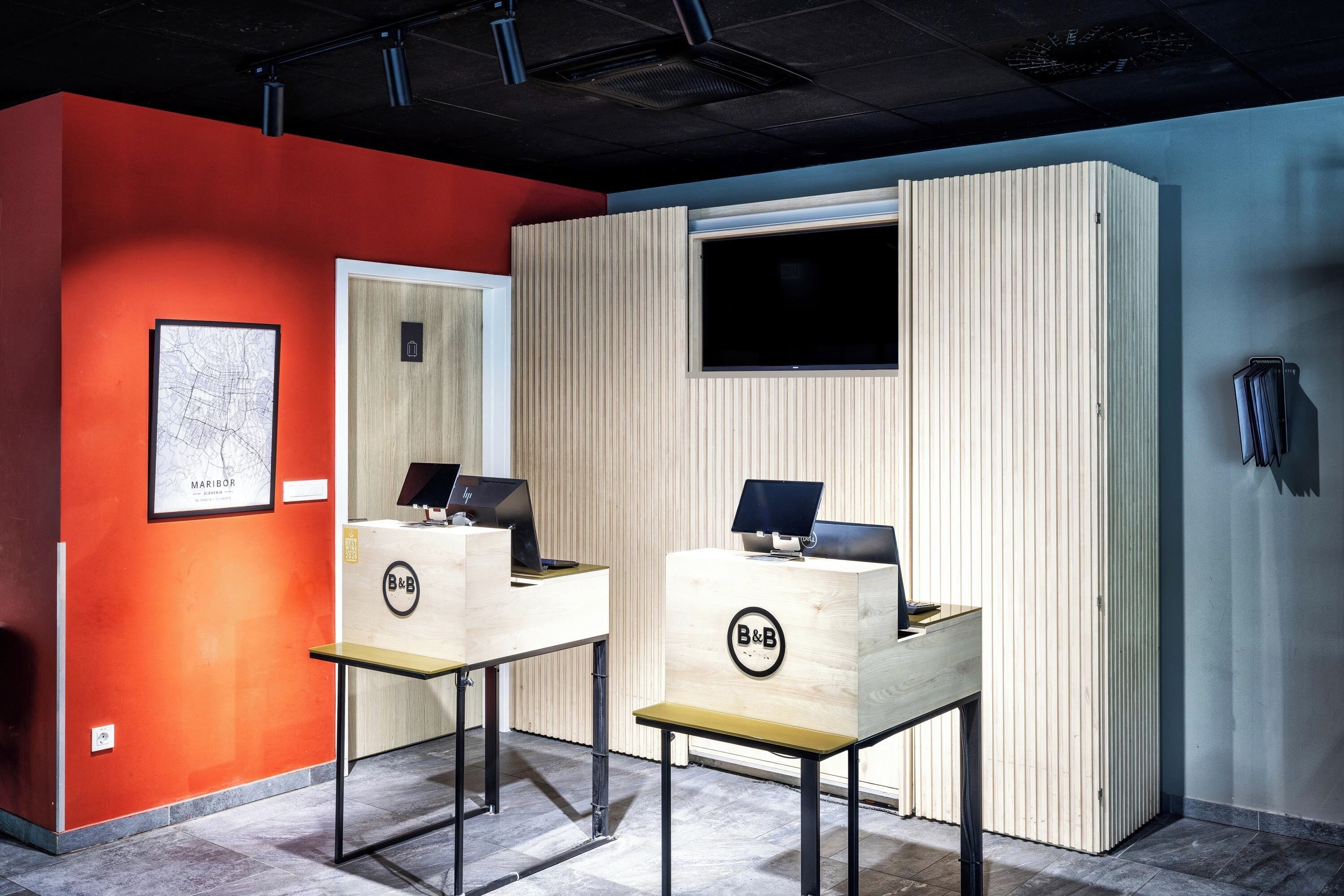 Une salle d’accueil avec deux bureaux en bois, une carte encadrée et une fenêtre.