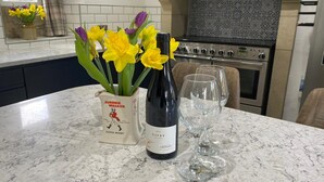 A kitchen counter with a bottle of wine, two wine glasses, and a vase with flowers. - Beautiful Peak District Cottage With Hot Tub (Hope Valley)