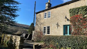 A stone building with a green door, a staircase leading to a stone wall, and a hedge in front. - Beautiful Peak District Cottage With Hot Tub (Hope Valley)