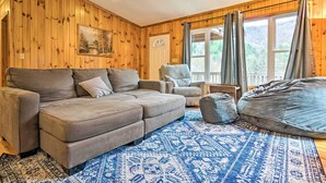 Una sala de estar acogedora con un sofá modular, una butaca, un sillón de peluche y una alfombra estampada.