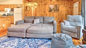 Una sala acogedora con un sofá seccional, un sillón reclinable y una alfombra.