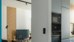 A modern kitchen with grey cabinets, a built-in oven, and a microwave. - Cozy Apartment with Balcony | Parking | Close to Park (Poznan)
