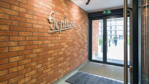 A brick wall with a sign that reads "Goplang" and a door leading outside. - Cozy Apartment with Balcony | Parking | Close to Park (Poznan)