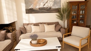 Ein Wohnzimmer mit Sofa, Sessel, Couchtisch und einer Vitrine.