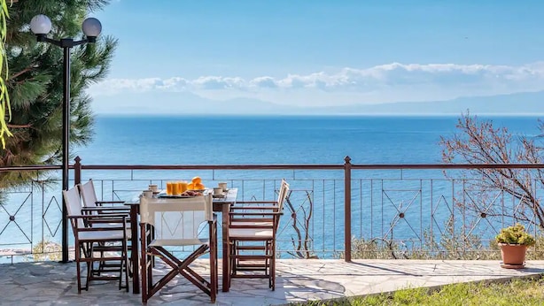 Eine Terrasse mit Tisch und Stühlen mit Blick auf die Küste.