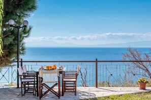 A terrace with a table and chairs overlooking a coastal view. - Quiet villa with breathtaking views, garden and private pool! (Glossa)