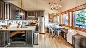 A modern kitchen with dark cabinets, stainless steel appliances, a large island, and a dining area with bar stools. - Mv8  lakeview across from Heavenly (Stateline)