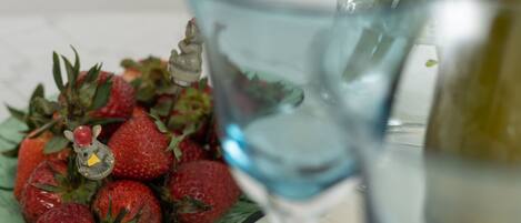 A plate of strawberries with a decorative figurine, a glass of water, and a bottle of olive oil.