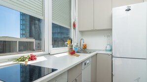 A modern kitchen with a built-in stove, a sink, and a white refrigerator. - Mina Apartment (Split)