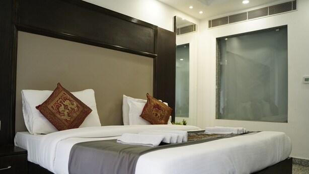A modern hotel room with a large bed, dark headboard, and a large window. - Hotel Anand Empire (New Delhi)