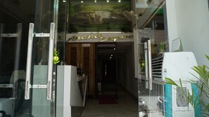 A hotel entrance with a glass door, a reception desk, and a sign reading "And Empire." - Hotel Anand Empire (New Delhi)