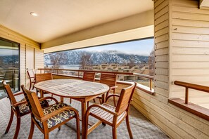 A wooden dining table with chairs, a view of a snowy mountain, and a balcony railing.