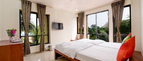 A modern hotel room with a large bed, a desk, a TV, and large windows with curtains.