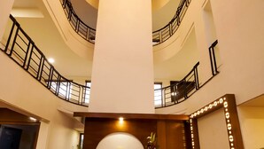 Interior de varios niveles con una recepción central, una lámpara decorativa en el techo y una escalera.