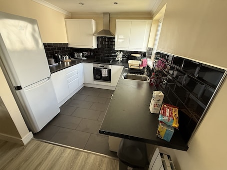 A compact kitchen with white cabinets, a black countertop, and a stainless steel sink.