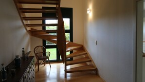 A modern interior with a spiral staircase, a wooden dresser, and a chair. - Wonderful vacation apartment on the Wieker Bodden (Wiek)
