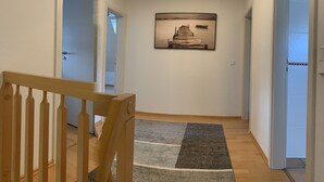 A hallway with a wooden chair, a rug, and a framed picture on the wall. - Wonderful vacation apartment on the Wieker Bodden (Wiek)