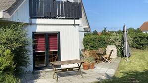 A two-story house with a balcony, a patio with outdoor furniture, and a well-maintained lawn. - Beautiful vacation home on Rügen (Wiek)
