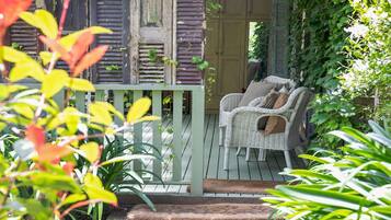 A wooden deck with wicker furniture and a door leading to a room.