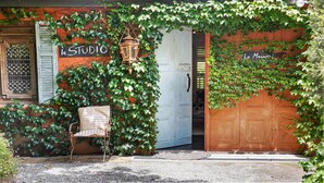 A building with a sign reading "Le Studio" and "La Maison" partially covered by ivy.