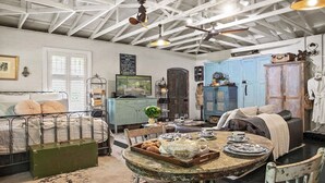 A room with a bed, a vintage table with tea set, a blue cabinet, and a ceiling fan.