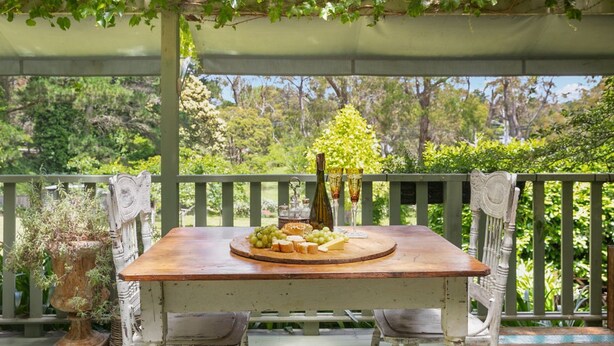 An outdoor dining area with a wooden table, chairs, and a pergola.