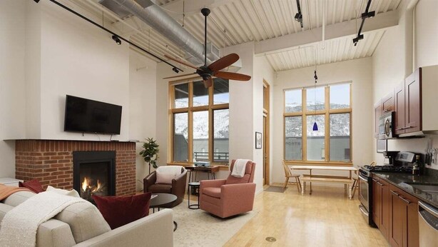 A spacious living area with a fireplace, seating, a dining table, and a kitchen area with cabinets and appliances.