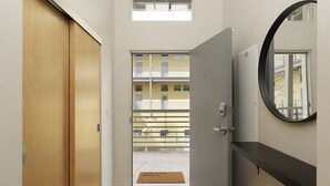 A hallway with a wooden door, a grey door, and a mirror on the wall.