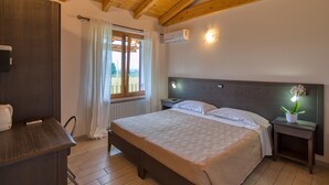 A bedroom with a wooden ceiling, a bed with white linens, a bedside table with a lamp, and a window with curtains. - HOTEL   VILLA CAMPO ROSSO (Lazise)
