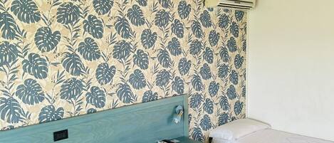 Una habitación con dos camas, vigas de madera en el techo y papel tapiz floral.