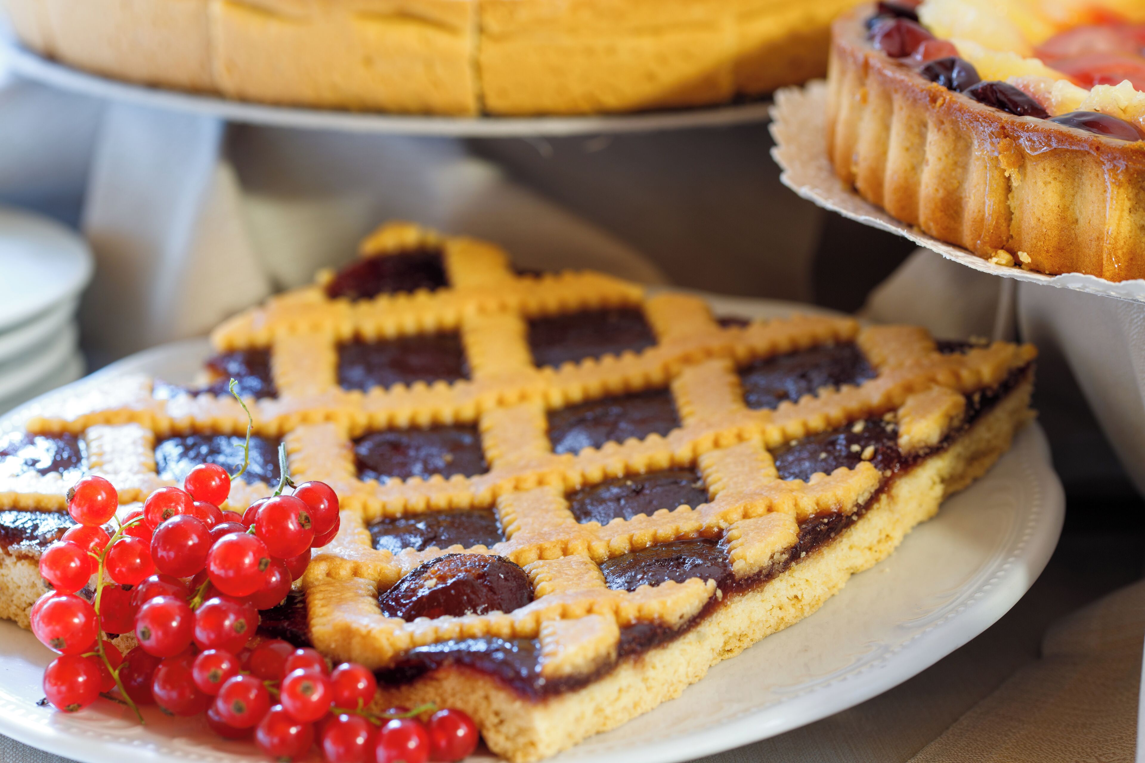 A dessert tray with a lattice-topped cake, a slice of pie, and red currants.
