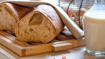 Een brood en een glazen fles op een houten ondergrond.
