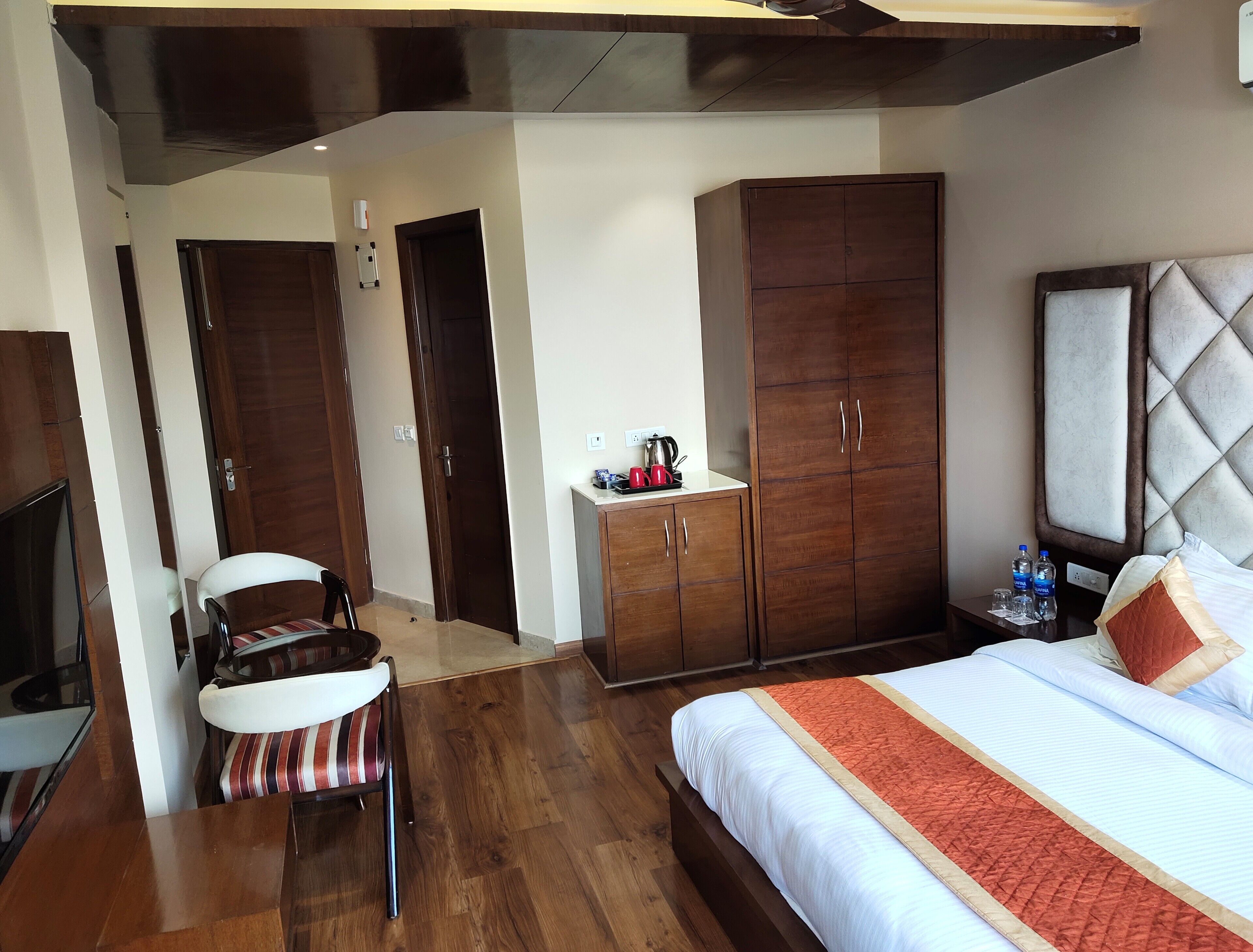 Une chambre d’hôtel comprenant un lit, une armoire, un bureau avec une bouilloire, une chaise et un téléviseur.