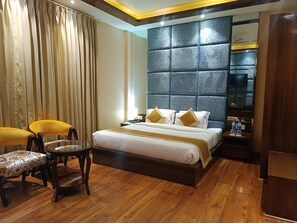 Een hotelkamer met een groot bed, een nachtkastje met een lamp, een stoel en een houten vloer.