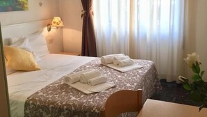 A hotel room with a bed, a desk, a chair, a lamp, and a painting on the wall. - Hotel Scandinavia (Massa)