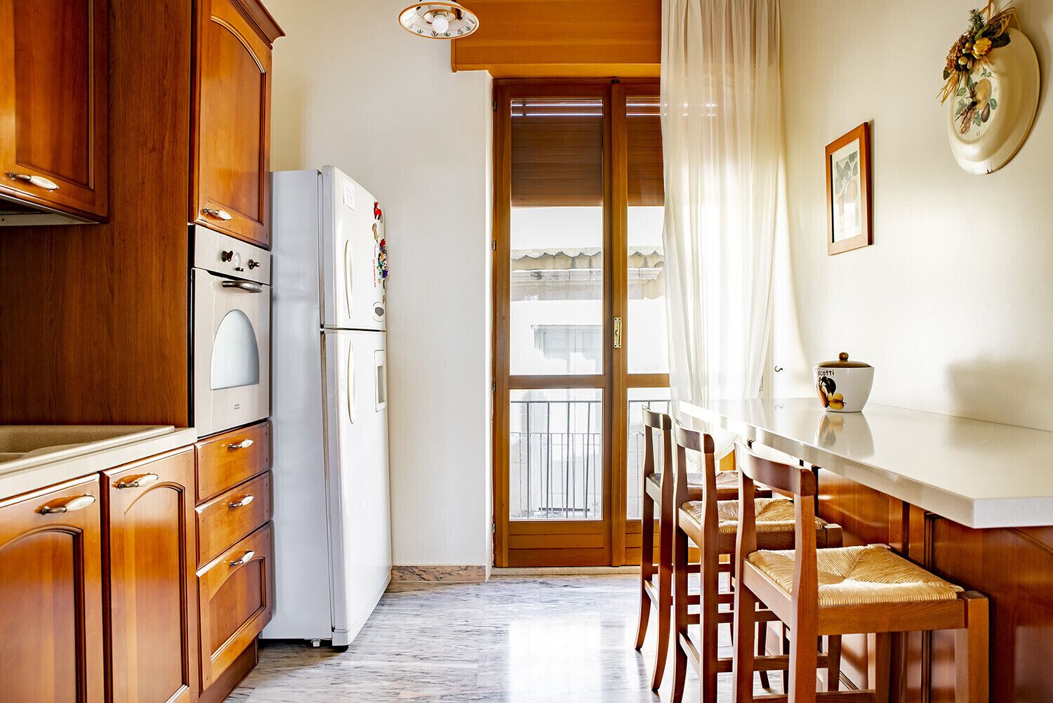 A compact kitchen with wooden cabinets, a white refrigerator, and a dining area with a table and chairs.