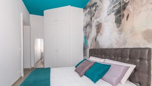 Un dormitorio con cama, armario y un cuadro abstracto grande en la pared.