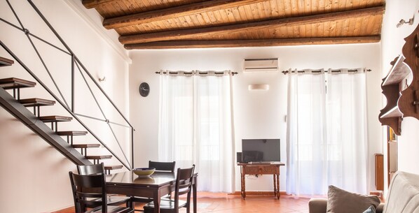 A modern living room with a staircase, a dining area, and a television. - Casa Meli in Piazza S. Domenico by Wonderful Italy (Palermo)