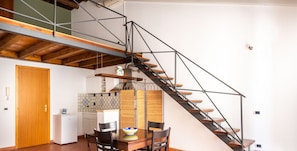 A modern kitchen with a dining area, featuring a staircase with metal railings and wooden steps. - Casa Meli in Piazza S. Domenico by Wonderful Italy (Palermo)