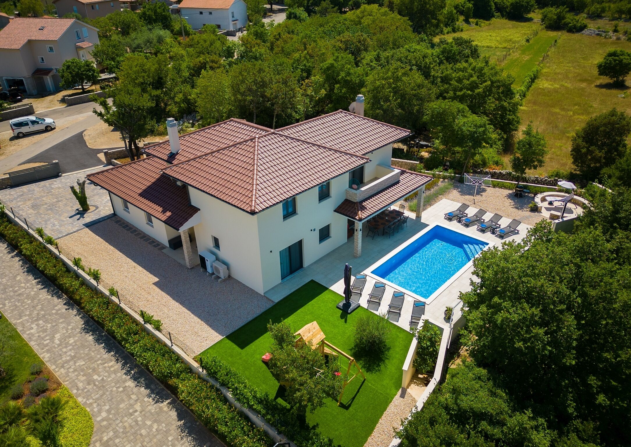 A two-story house with a swimming pool, a patio with outdoor furniture, and a well-maintained lawn.