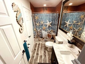 A bathroom with a nautical theme, featuring starfish decorations, a wooden floor, and a marble countertop.