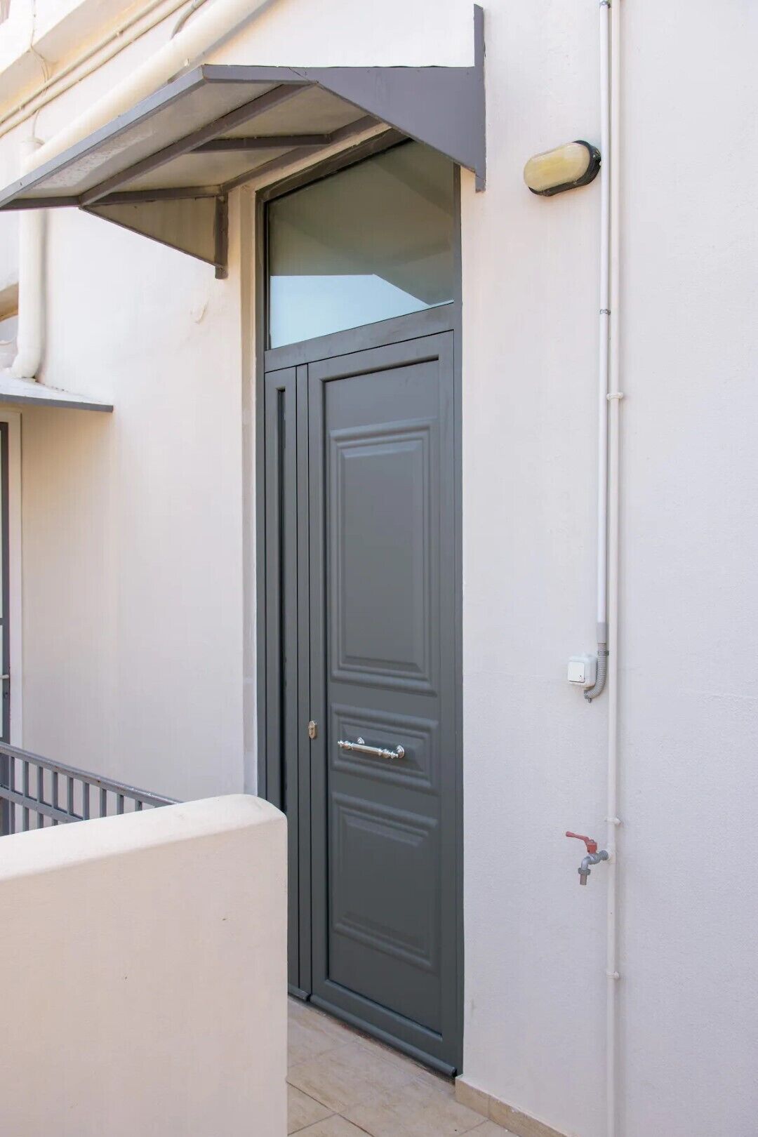 A dark grey door with a glass panel, a metal handle, and a small window above it.