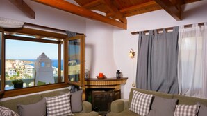 Uma sala de estar acolhedora com sofá, lareira e vista para o mar.