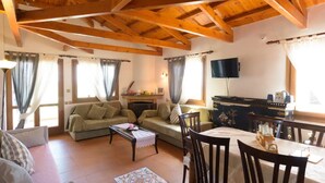 Uma sala de estar acolhedora com sofá, mesa de centro e área de jantar com cadeiras e mesa.