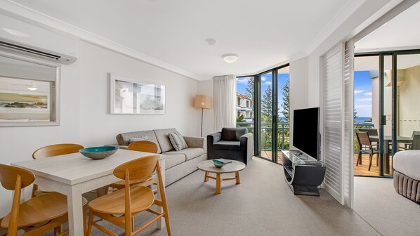 Relax in this stylish living area with a dining table, sofa, and large windows offering a view of the outdoors.
